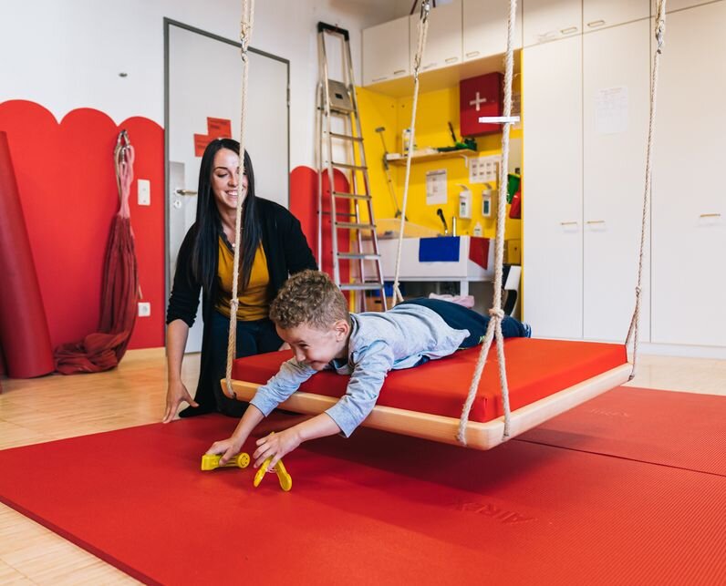 Eine Frau mit einem Jungen in einem Turnraum.