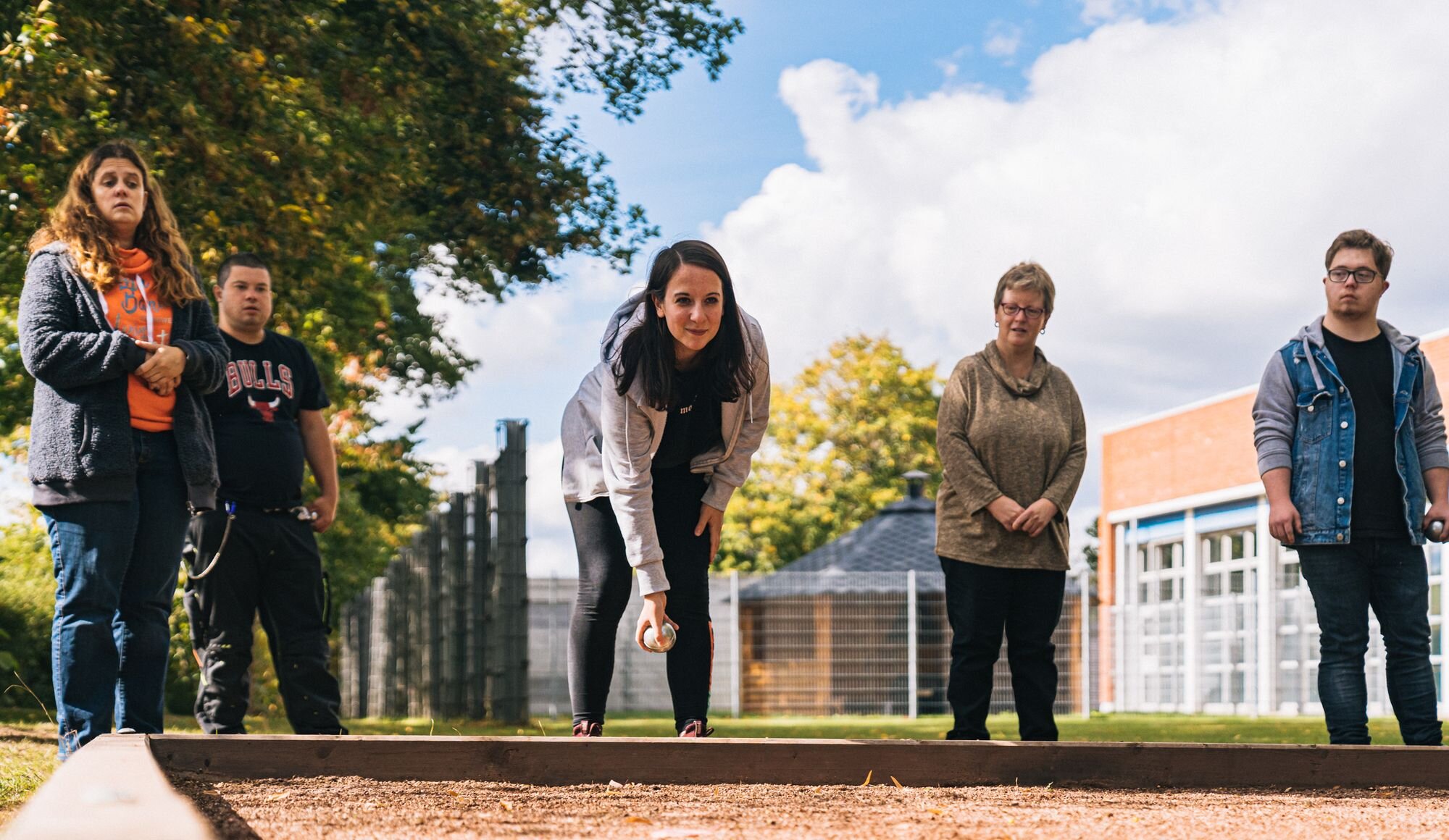 Personen spielen Boules. Sie schauen konzentriert. Eine Person wirft gerade.